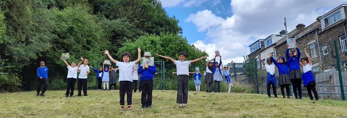 Children on a school field holding drawings